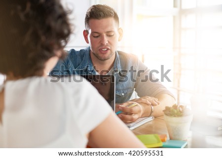 Image of two succesful business people using a laptop during conversation