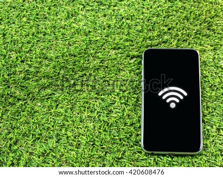 Wifi sign on smart phone on grass; connected concept background