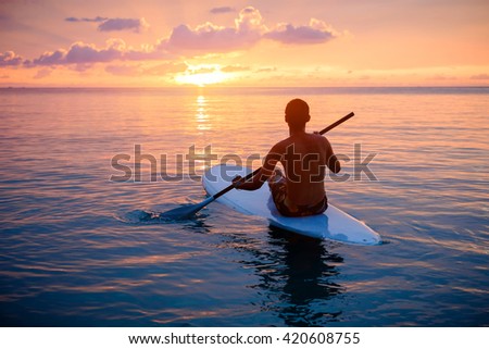 Silhouette of man paddling on paddle board at sunset. Watersport near the beach on sunset Royalty-Free Stock Photo #420608755