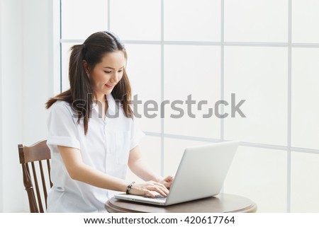 Beautiful woman working from her home office on a laptop computer sitting at a desk surfing the internet