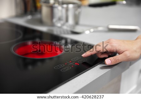 Female hand turns on electric hob closeup Royalty-Free Stock Photo #420628237