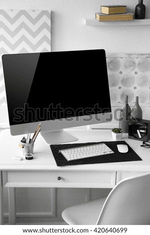 Modern wide screen monitor on white table in room interior
