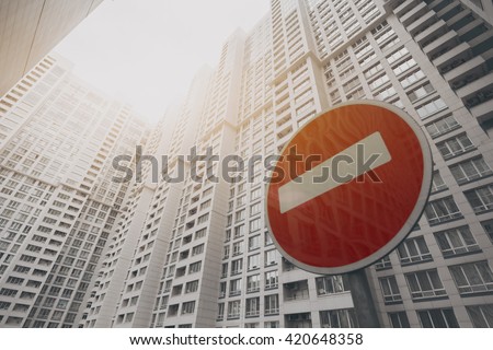 Contemporary white and grey skyscraper apartment building in Moscow on a sunny day with a red stop road sign, reflecting the building, view from bottom 