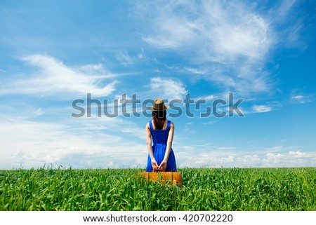 photo of young beautiful woman with suitcase in the field