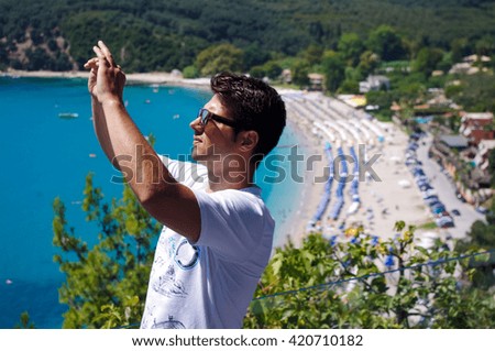 Young man hold cellphone, take picture of summer beach. Panoramic sea view.