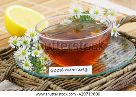 Good morning card with cup of chamomile tea with chamomile flowers and fresh lemon
