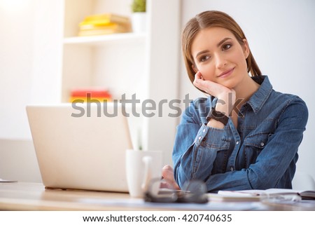 Positive delighted  woman sitting at the table  