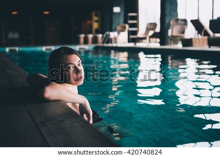 A young beautiful woman swims in a pool. Wellness concept. Calmness and relax, woman happiness. Toned picture