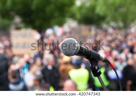 Protest. Public demonstration. Microphone in focus against blurred audience. Royalty-Free Stock Photo #420747343