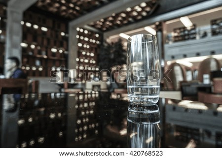 A glass of water on the table in lounge bar background.