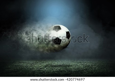 Moving soccer ball around splash drops on the stadium field. Royalty-Free Stock Photo #420774697