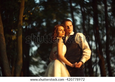 Bright and blurred - wedding couple hold their hands together standing in the lights of sun