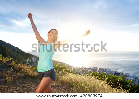 Portrait of smiling athletic woman with arms outstretched 
