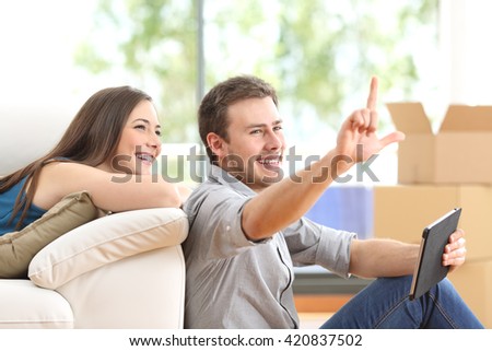 Couple planning decoration on line with a tablet and moving home in the living room Royalty-Free Stock Photo #420837502