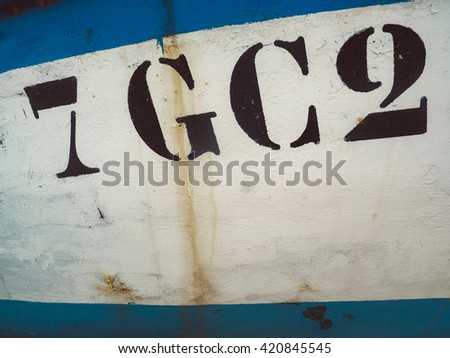 Close-up of numbers and letters on the side of a fishing boat - background