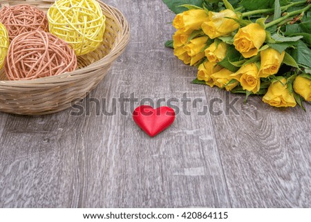 Yellow roses and red heart on a wooden background