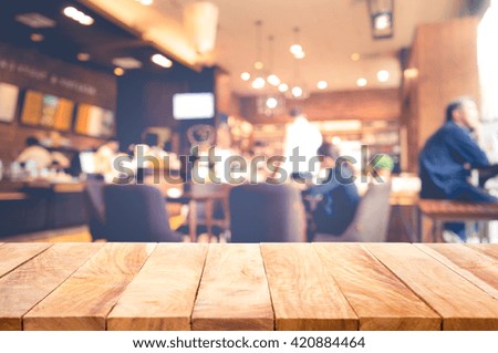 Wood table top on blur cafe restaurant in light gold background.For create product display or design key visual layout