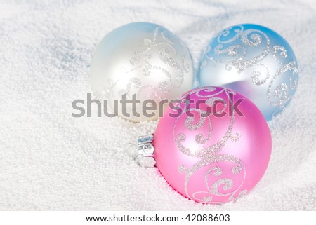Tender Christmas bauble of rose, blue and white color on to snow.
