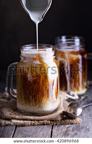 Iced coffee with milk in mason jars  on the table