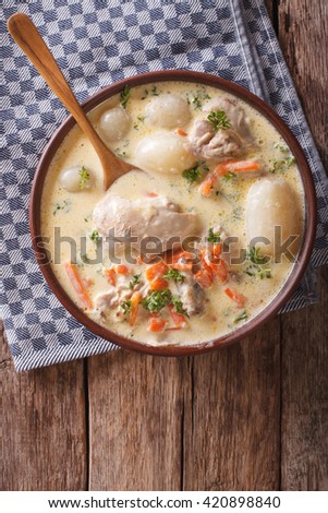 Creamy soup with chicken and vegetables close up in a bowl on the table. Vertical view from above
