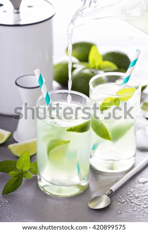 Refreshing cold cocktail with ice, mint and limes