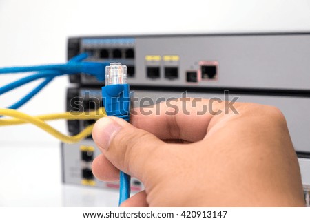 Close-up Hand holding ethernet cable on network switches background
