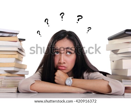 Confused female student laying between stacks of books, looking up with many question on her head, over white background Royalty-Free Stock Photo #420916372