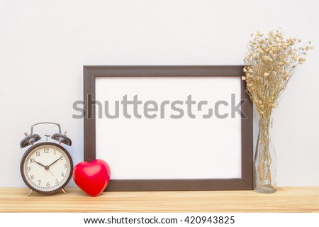 Blank frame, alarm clock and heart on the table, mock up