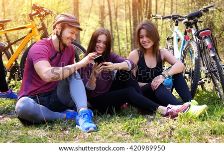 Two females and one male using smartphone in a park.