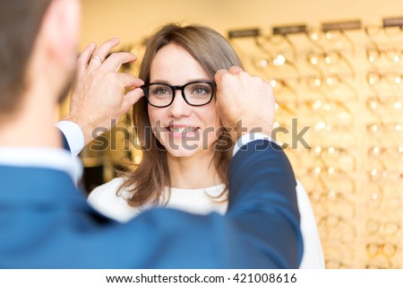 View of a Young attractive  woman testing new glasses with optician Royalty-Free Stock Photo #421008616