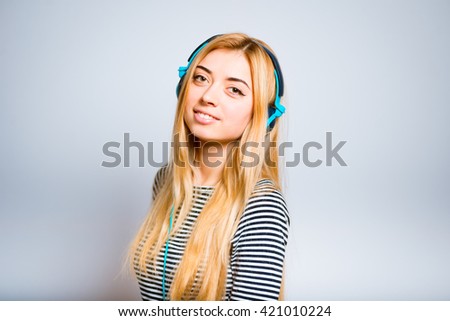 Pretty blond girl listens to music on headphones with the phone, isolated on white background