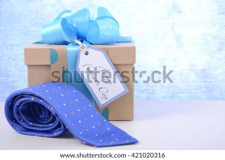 Happy Fathers Day gift and necktie on white wood table and pale blue background. 