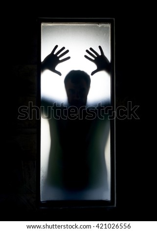 Shadowy figure behind glass.  Dramatic film grain Royalty-Free Stock Photo #421026556