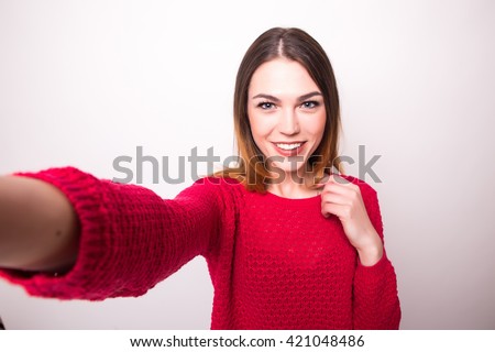 Happy cute woman making selfie over gray background.