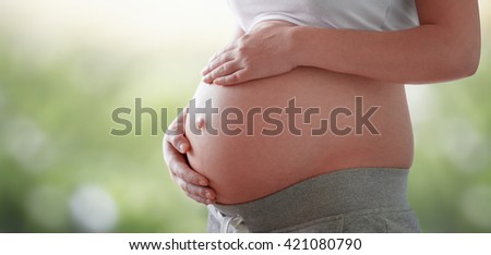 belly of a pregnant woman on a light natural background