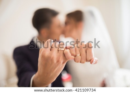 Unfocused couple showing hands with wedding rings and crossing small fingers