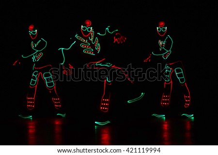 dancers in led suits on dark background, colored show 