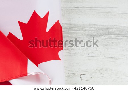 Canadian flag folded creatively on white rustic wooden table. Horizontal image with copy space.