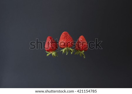 one red flying Strawberry in focus and two red on the soft board blurry background