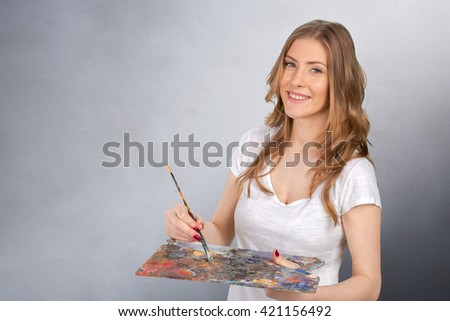 Young beautiful woman holing paintbrush and palette