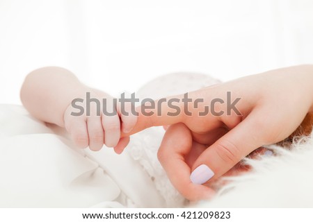 Newborn baby grasping her mother's finger. Concept of child care, feeling safe, parent love. Royalty-Free Stock Photo #421209823