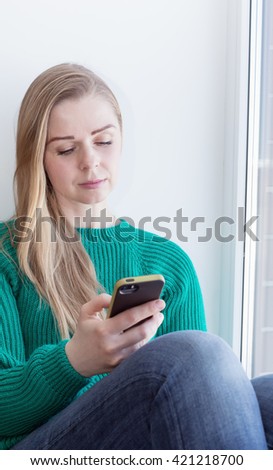 A blonde woman surfing the internet with her smartphone on white background