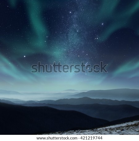 Starry night sky with aurora polaris over the mountains Royalty-Free Stock Photo #421219744