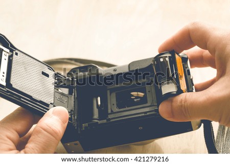 man installing a photo film cartridge in a film camera  - vintage style