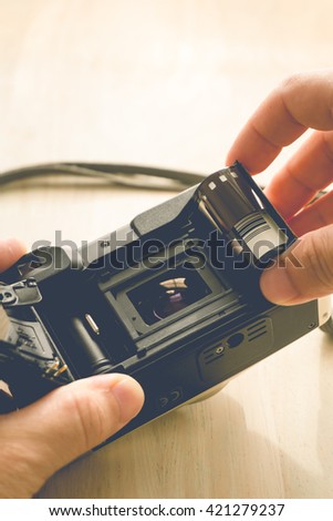 man installing a photo film cartridge in a film camera  - vintage style