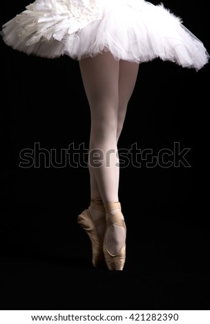 Legs of ballerina and a white tutu on a black background
