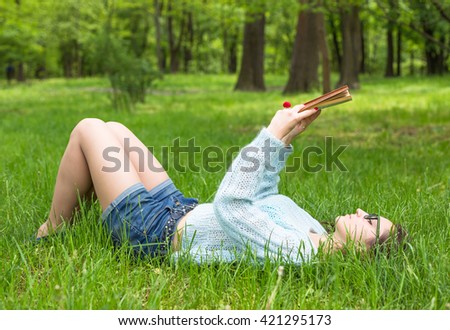 Stylish student girl relax with book in beautiful summer park at sunny day. Outdoor lifestyle picture