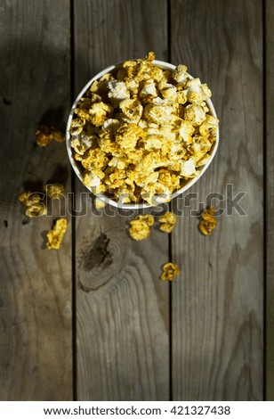 Bowl with popcorn on wooden background, view from above