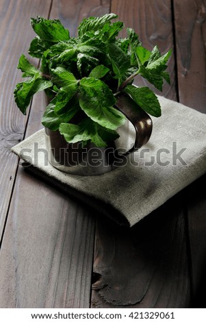 Fresh mint in the stainless cup on the rustic cloth the wooden background.Free space