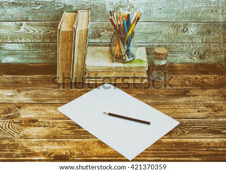Old books and pencils on a wooden table on a wooden background. Vintage or retro tone